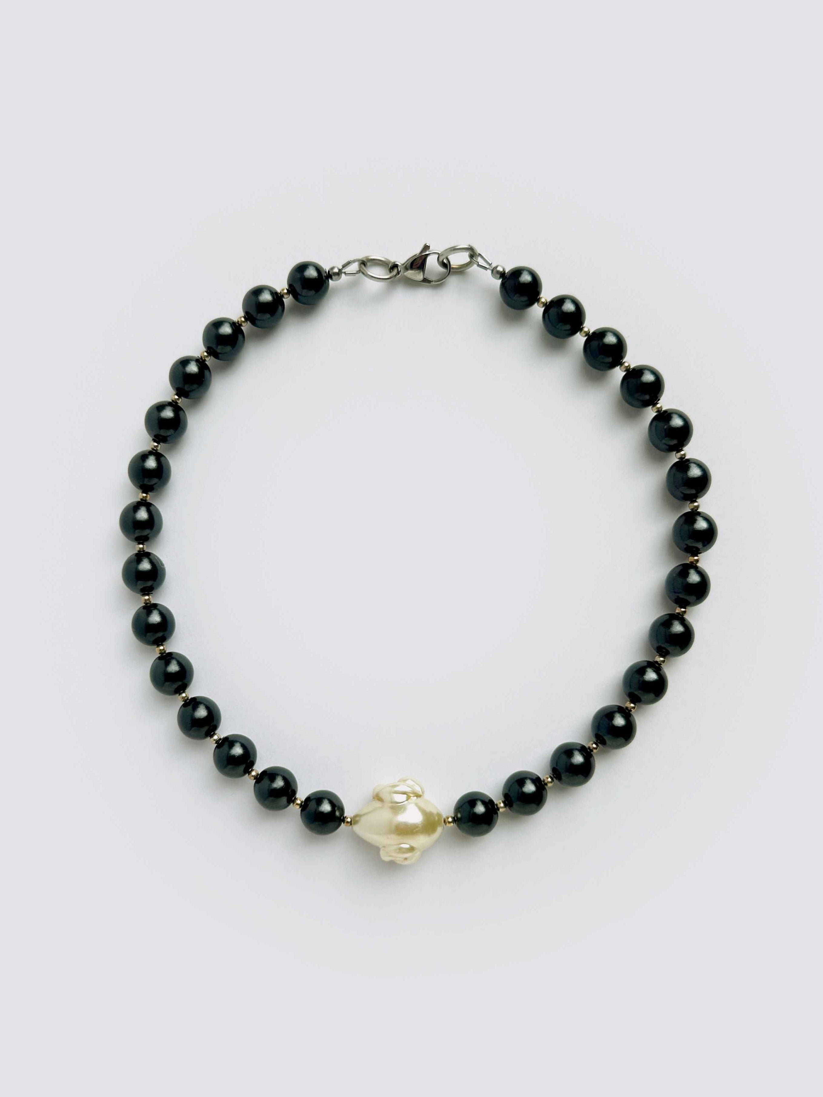 Black beaded bracelet with a gold clasp on a white background