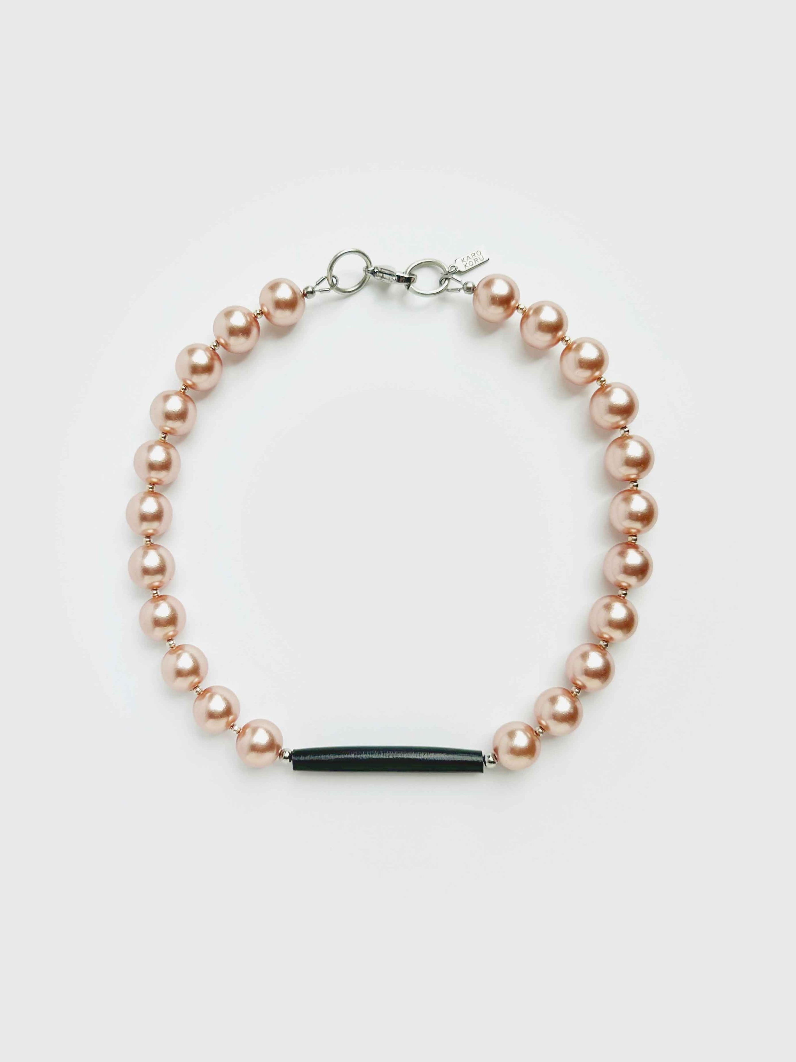 Pearl bracelet with a black bar charm on a light gray background
