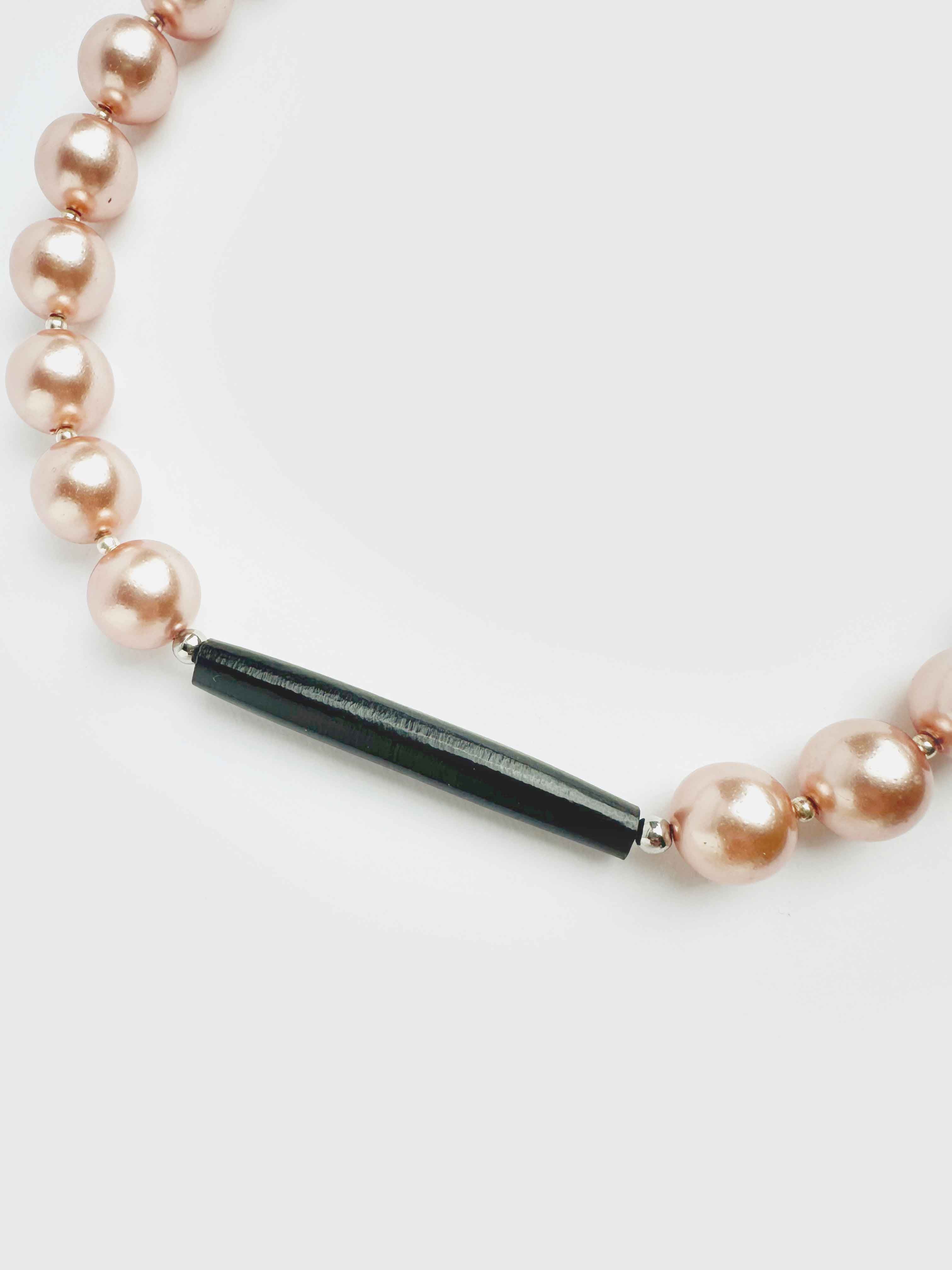Pearl necklace with a black bar clasp on a white background
