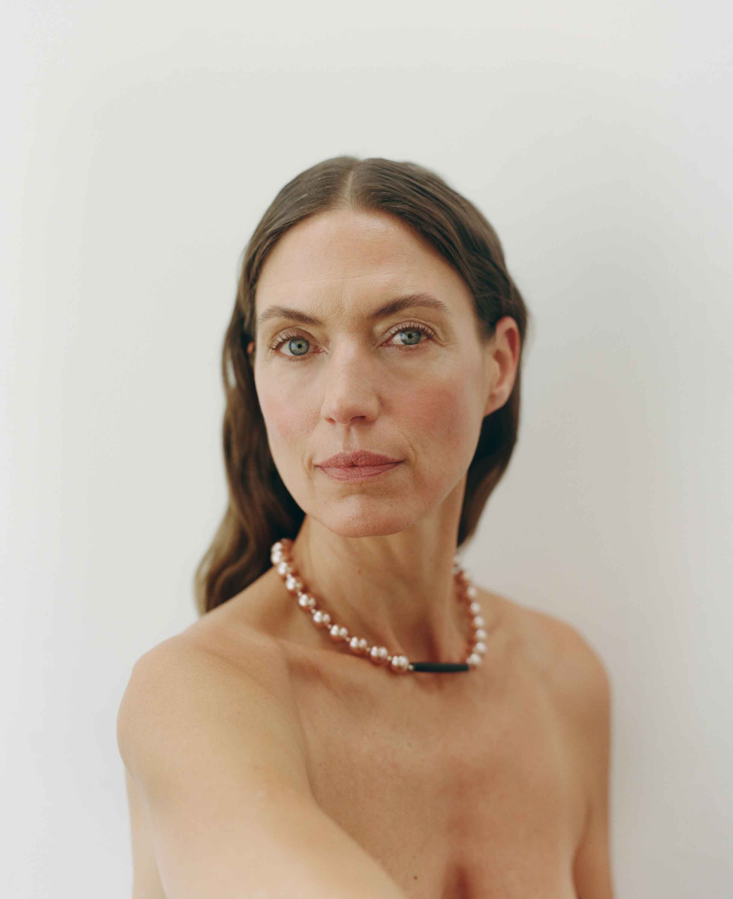 Woman wearing a pearl necklace against a plain background