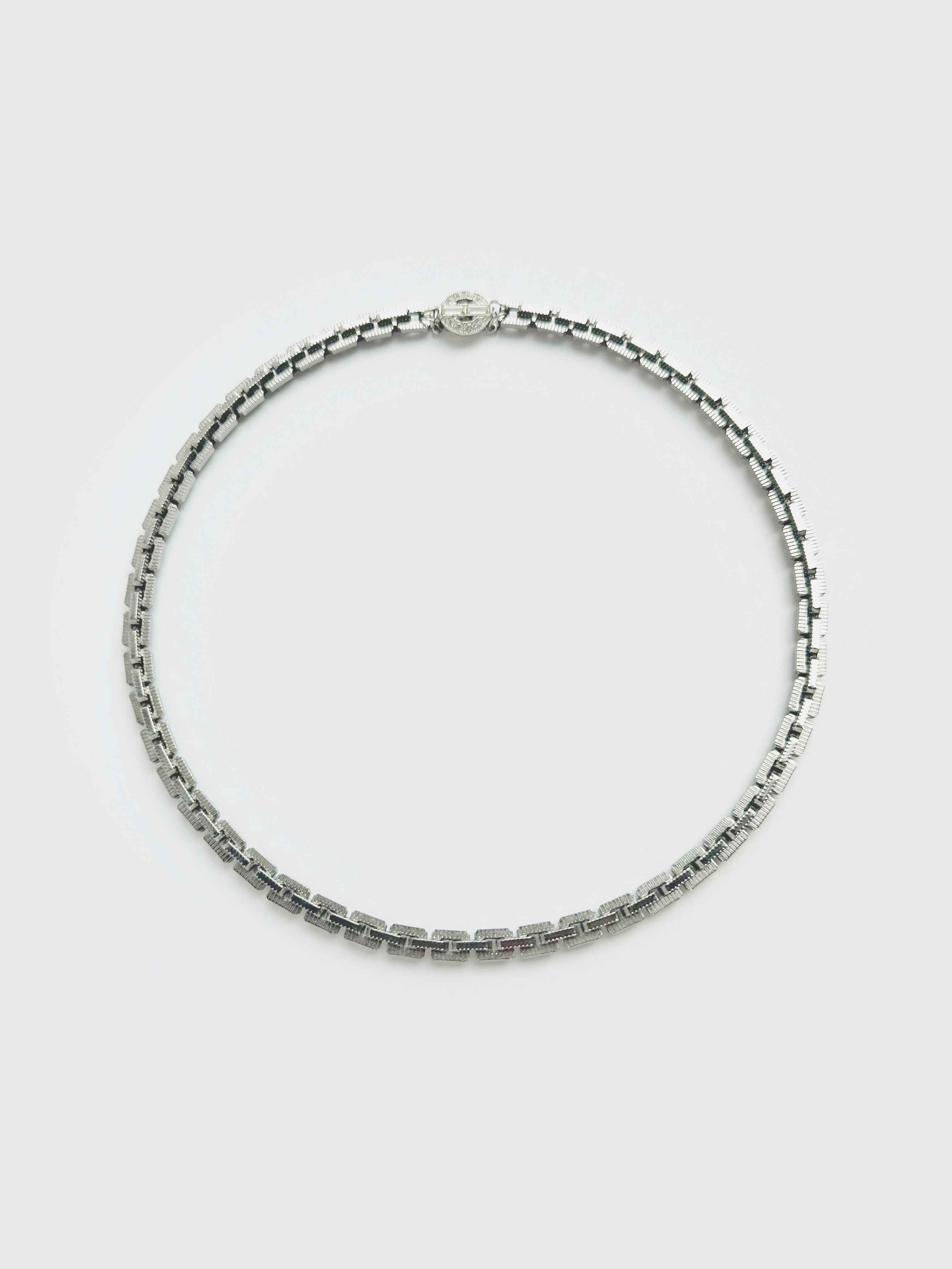 Silver beaded necklace on a light gray background