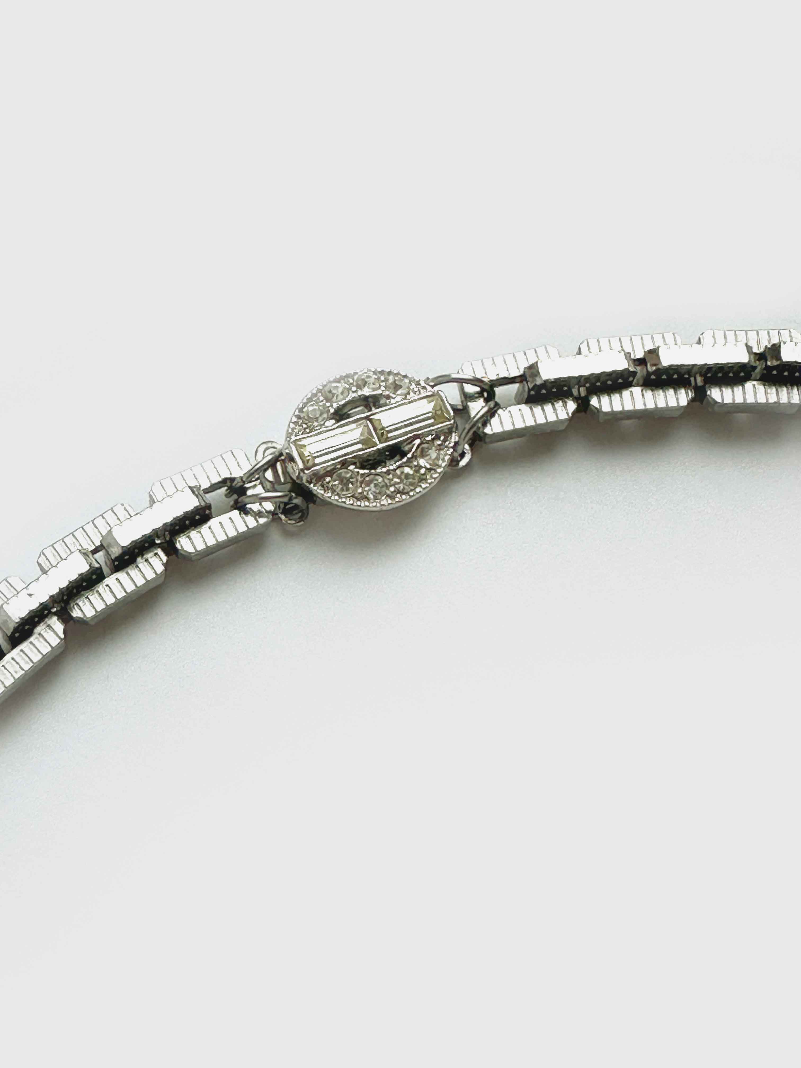 Silver bracelet with a decorative clasp on a white background