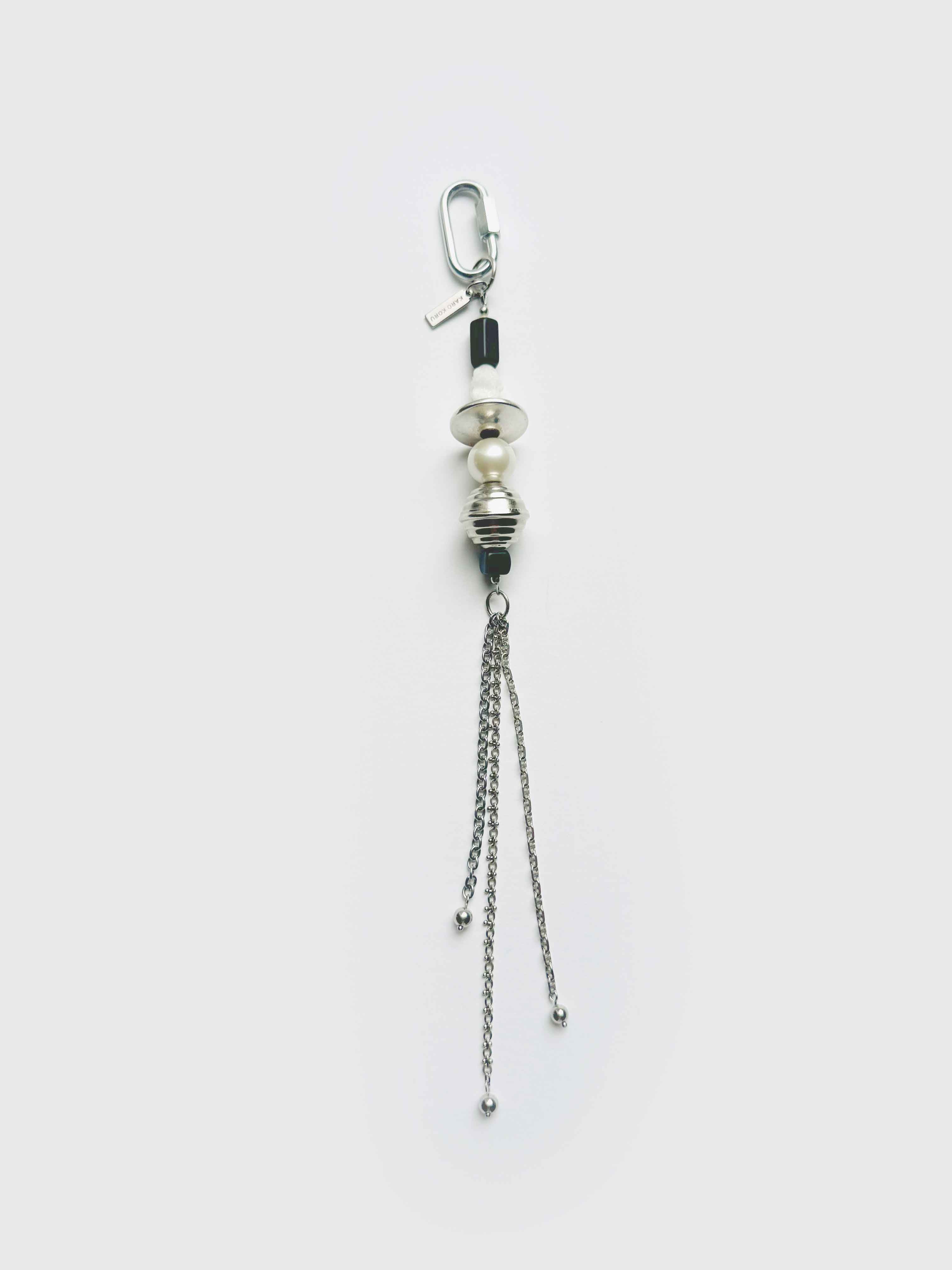 Handbag charm with vintage bead and chains on a white background.