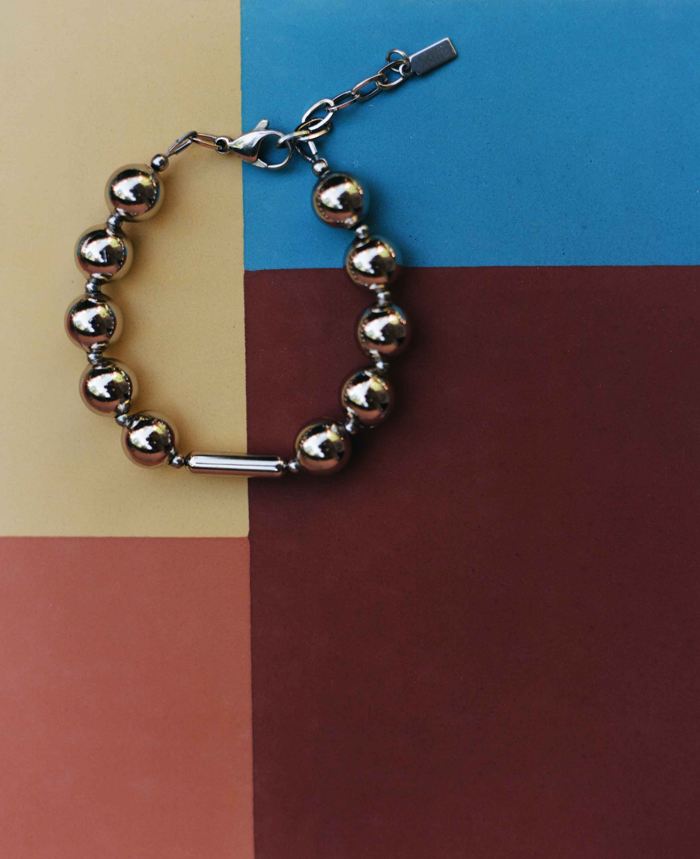 Silver beaded bracelet on a multicolored geometric background