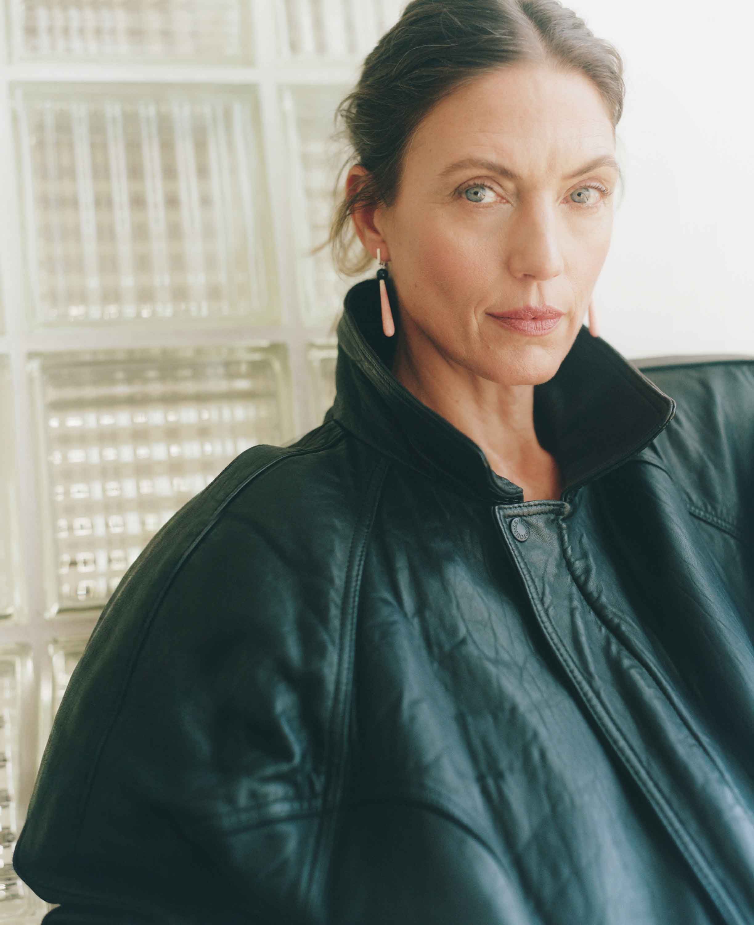 Woman wearing a dark green jacket in a softly lit room.