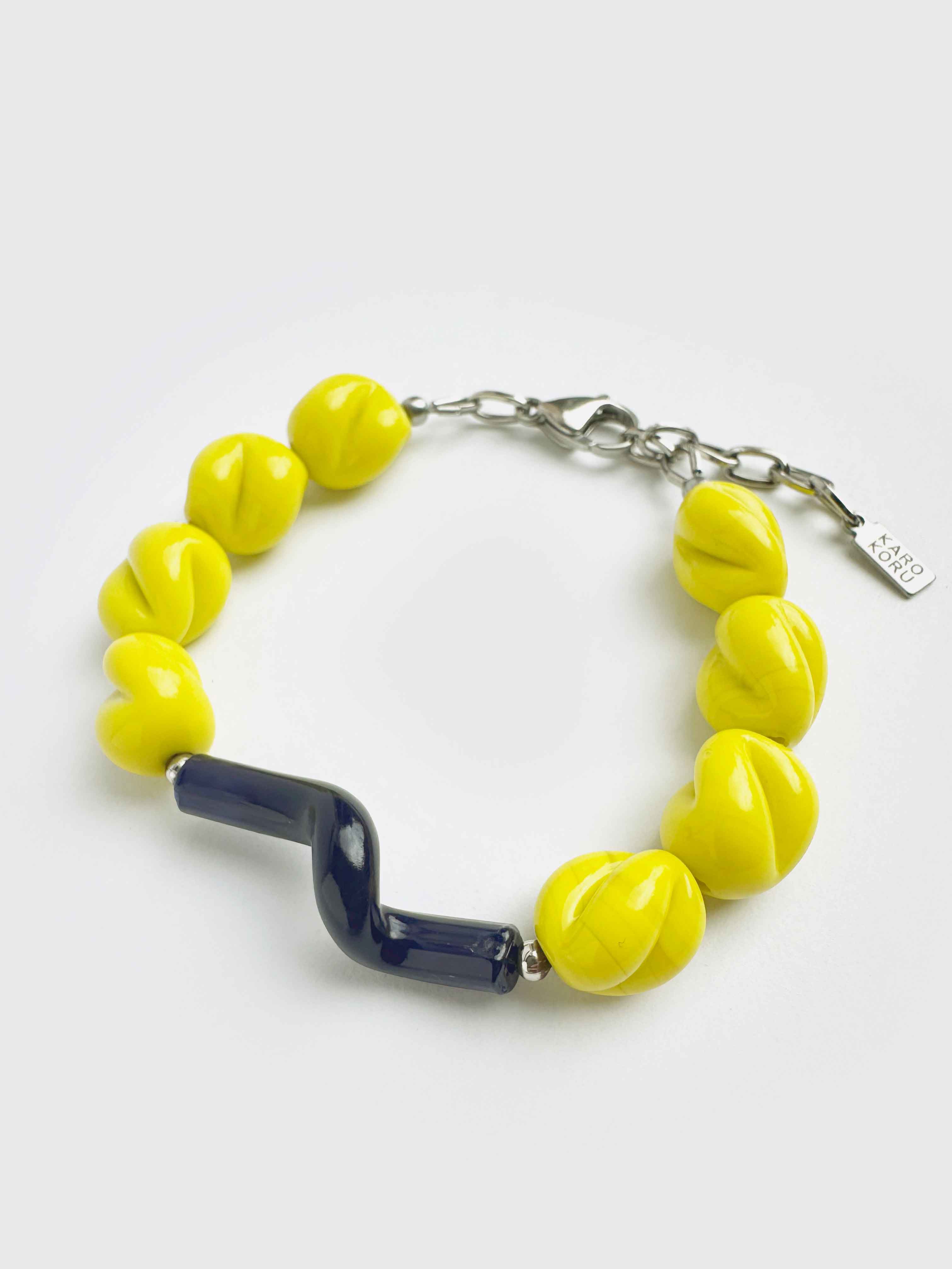 Bracelet with yellow beads and a blue accent on a white background