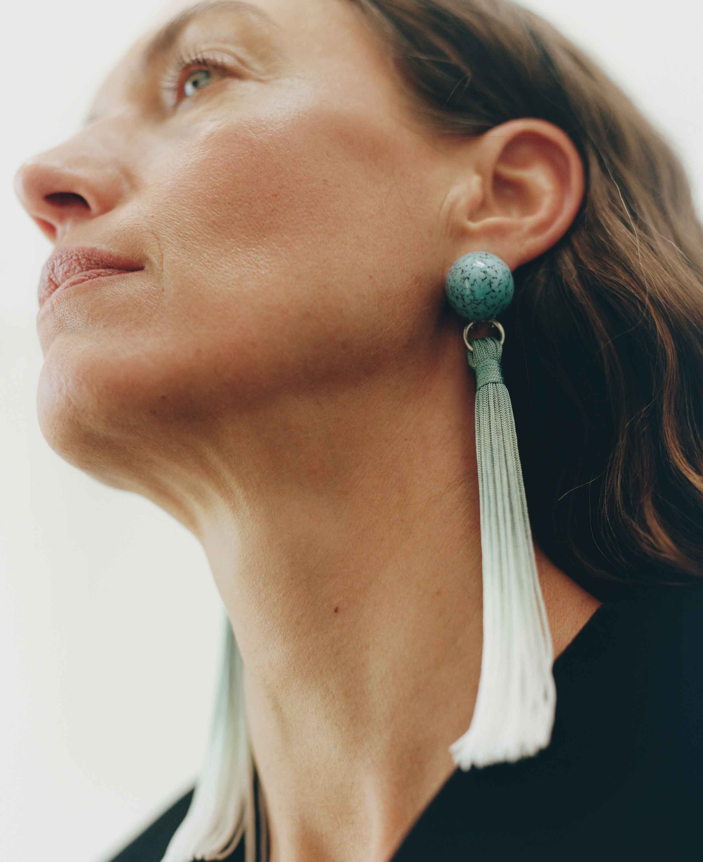 Close-up of a woman wearing a tassel earring with a white background