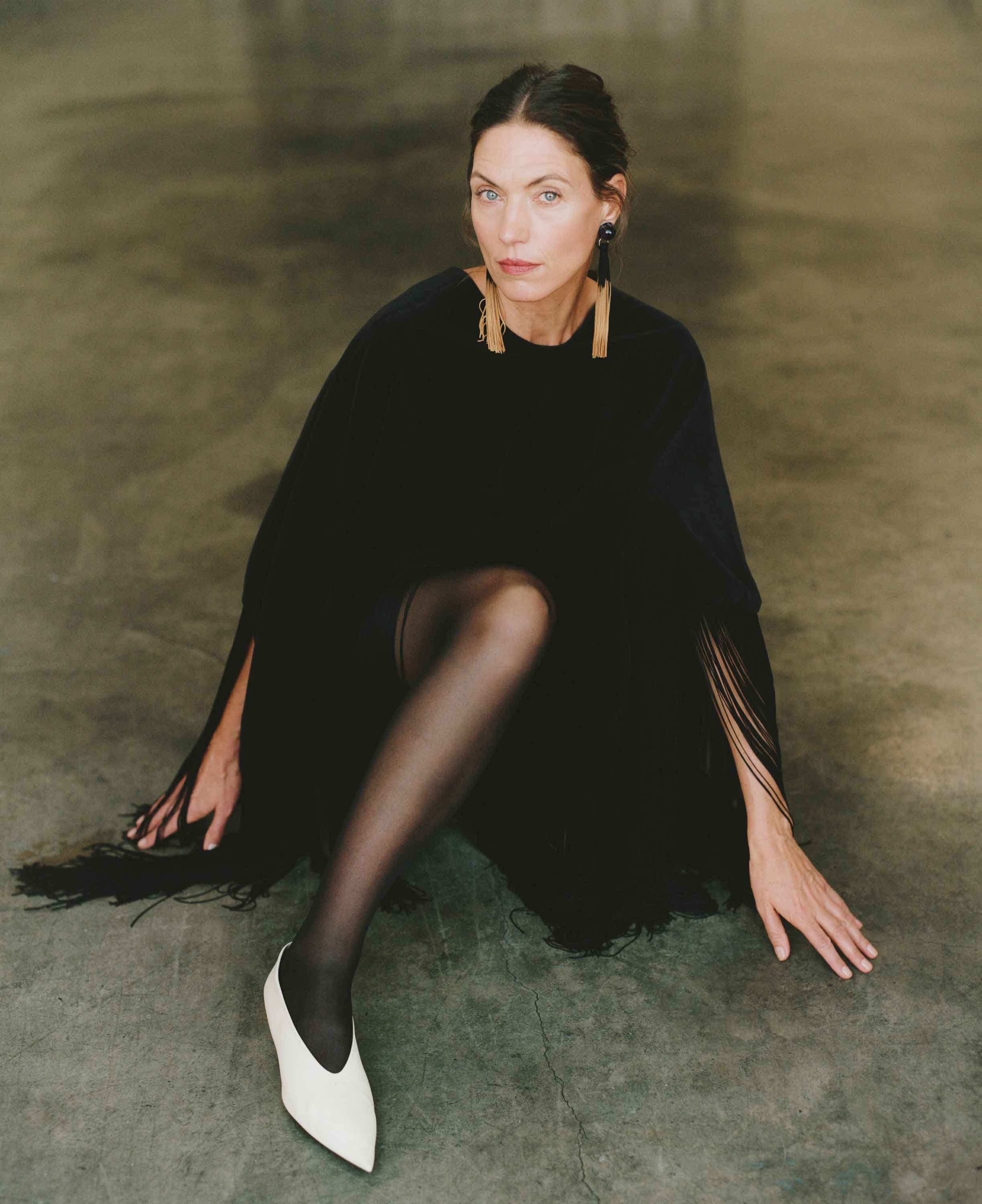 Woman in a black dress sitting on a textured floor