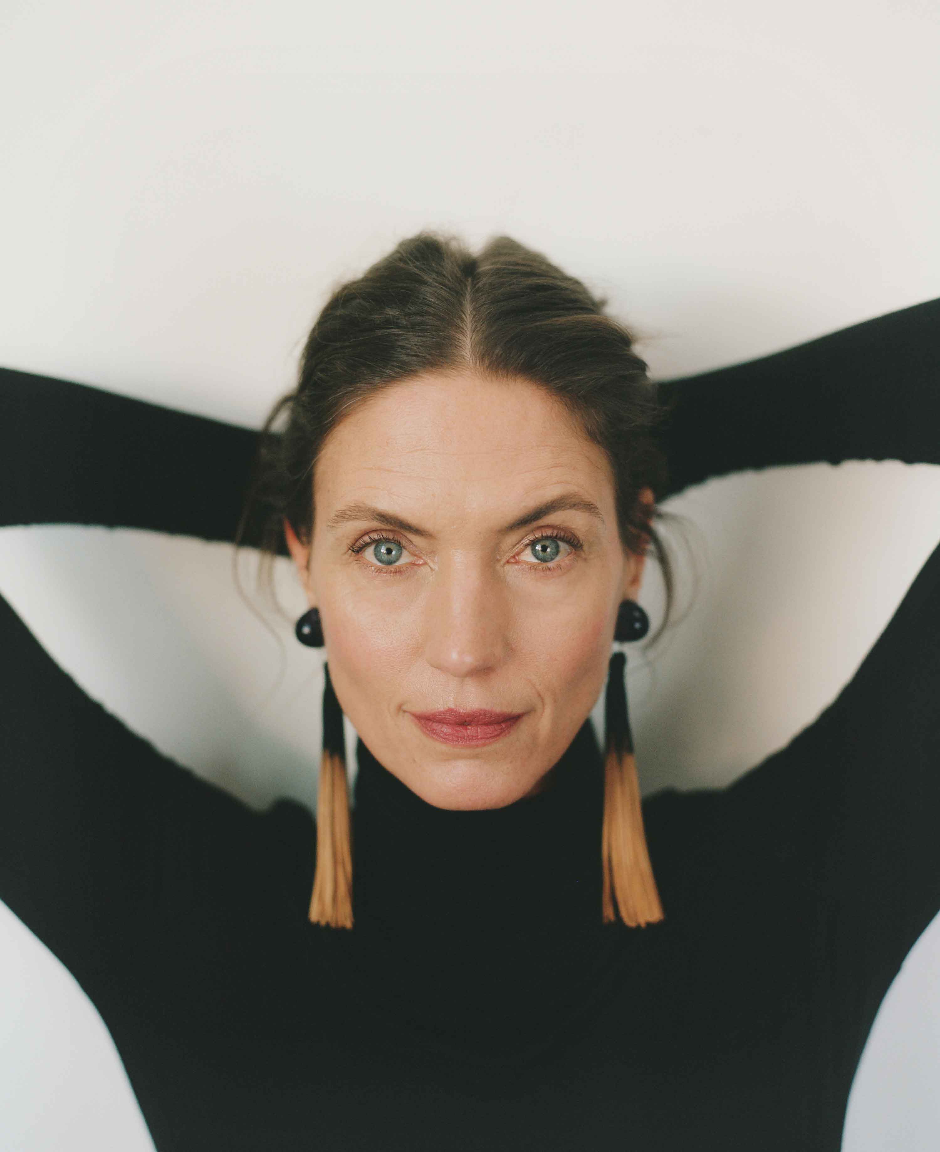 Woman wearing large hoop earrings with long tassels against a white background