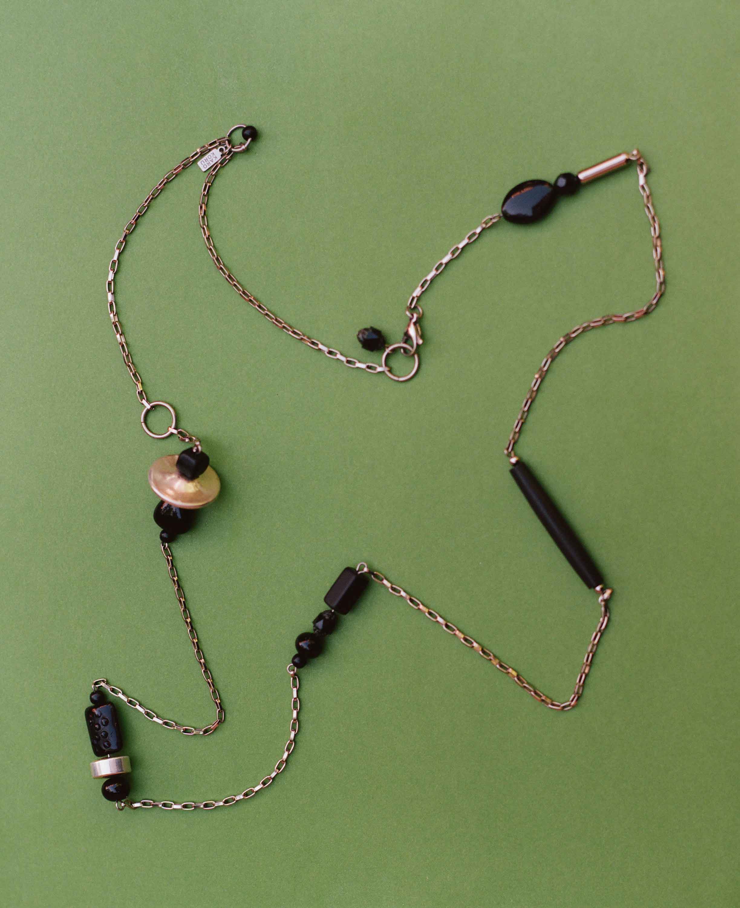 Necklace with black beads on a green background