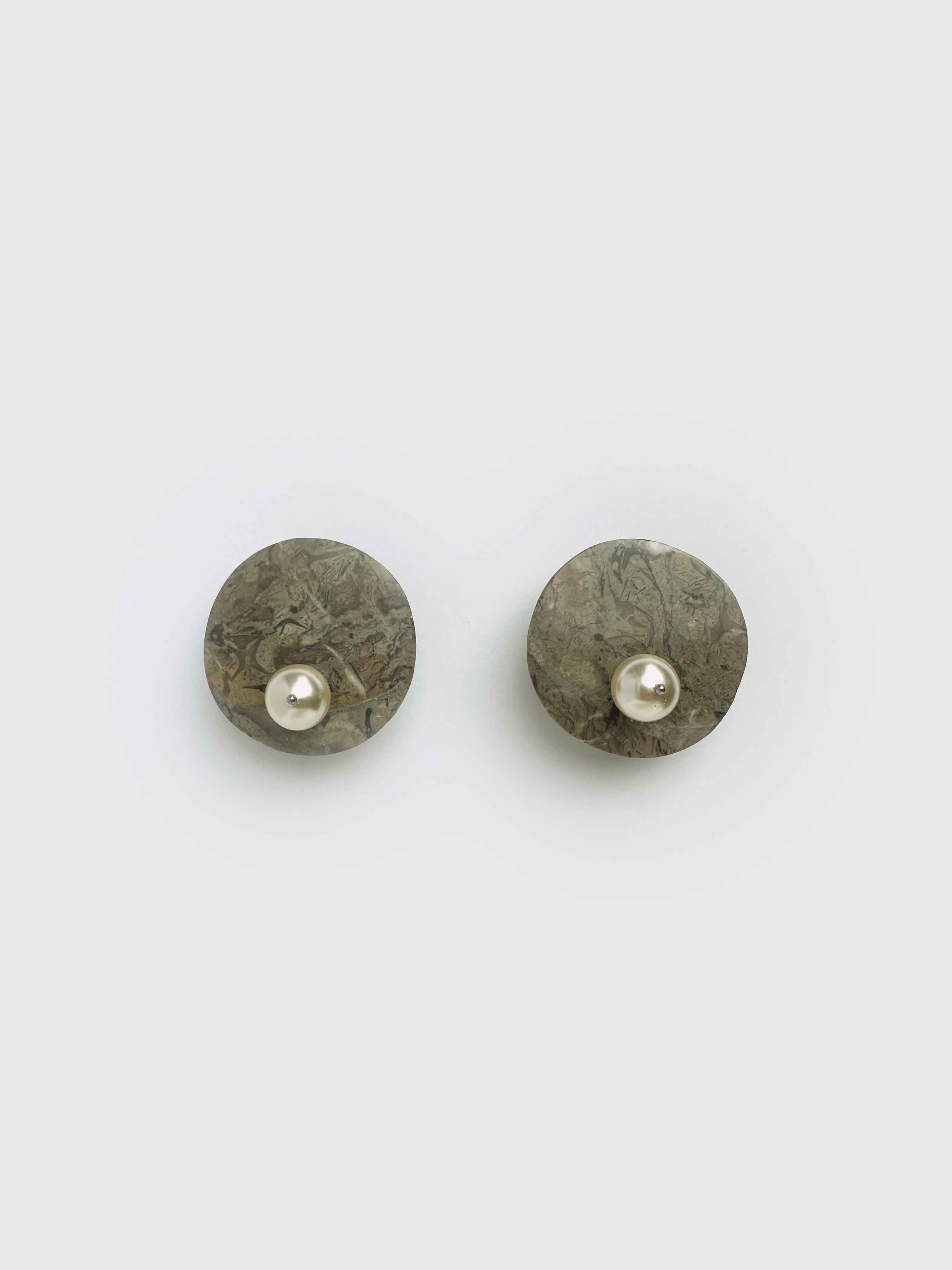 Stone earrings with pearls on them on a white backround.