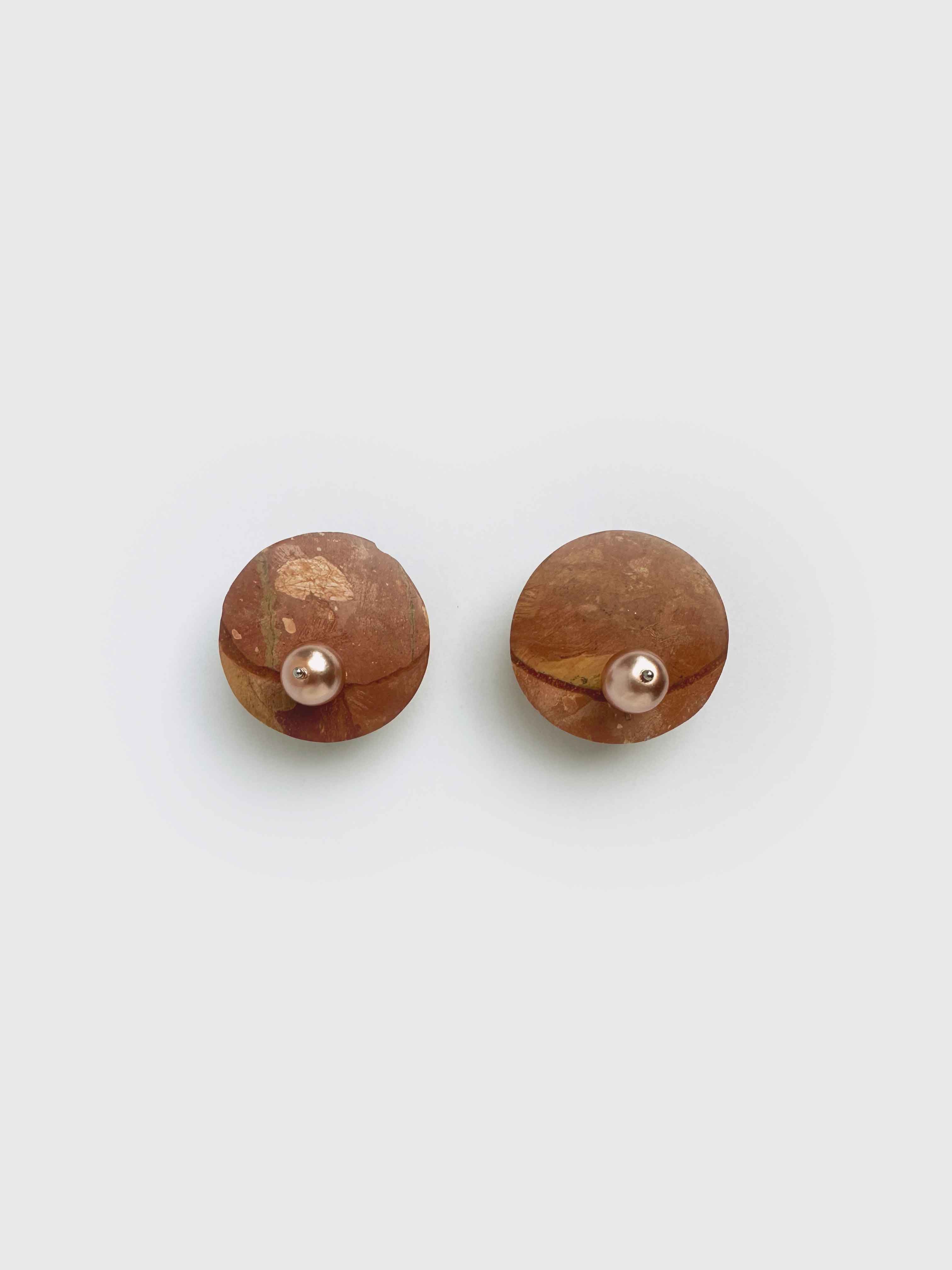 Brown stone like disc earrings with pearls on white background.

